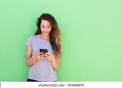 Front Portrait Of Beautiful Young Woman Holding Smart Phone On Green Background