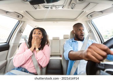 Front Portrait Of Scared African American Young Couple Driving Car On High Speed And Survived An Accident. Shock Reaction. Lady Closing Covering Mouth, Looking At Crash Or Animal On The Road