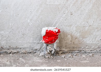 In front of a pristine white wall, there is a striking red object sitting directly on the ground, capturing attention effortlessly