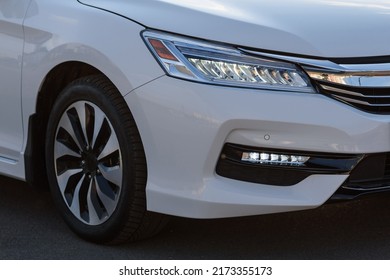 Front right headlight on modern white new car. Detail white metallic bumper car with light and car wheel. Lamp signals for turn a car on street. Exterior automobile closeup.