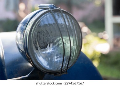Front round optic of an old abandoned blue car.