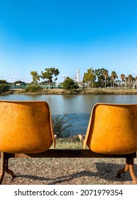 A Front Row Seat To Nature Concept. Two Old Vintage Orange Seats On The River Bank In The Park