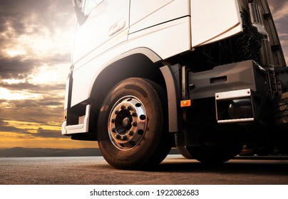 Front of semi truck parked at sunset sky. Close-up a big truck wheels. Industry freight truck transportation.