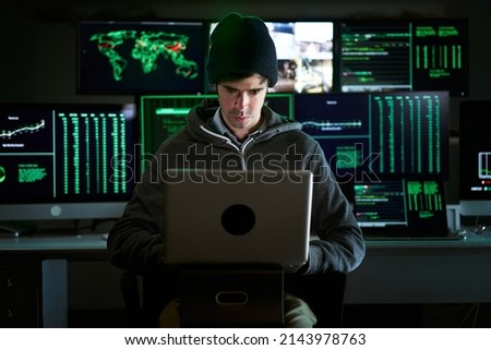 Front Shot from to Hacker Breaking into Corporate Data Servers from His Underground Hideout. Place has dark atmosphere, multiple displays