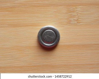 Front side of small silver round internal magnet of over the ear headphone kept on wooden table