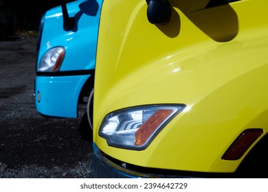Front side view of two trucks. One yellow and one blue.