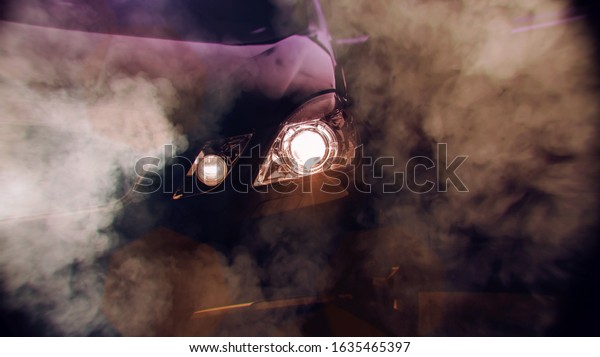 Front of a sports car with smoke.\
Close up detail on one of the headlights modern\
car.