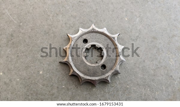 Front sprocket of motorcycle lying on the\
ground. Spare parts of two\
wheeler.