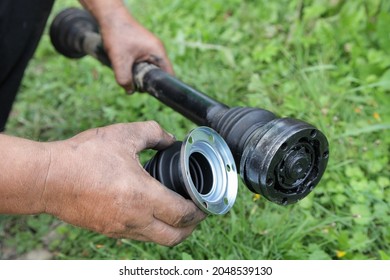 Front Suspension Driveshaft With CV Joint Constant Velocity Spheric Tripod In Serviceman Hands Outdoor On Green Grass Background, DIY Car Repair