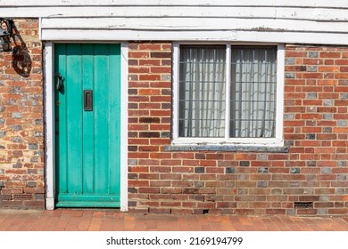 Front of typical small old terraced house with a light green door in an English village street