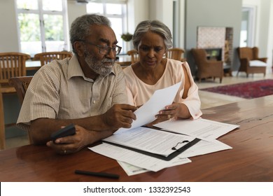 Front View Of An Active African American Senior Couple Discussing Over Invoices In The Living Room At Home