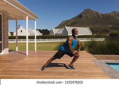 Front view of an active senior African American man performing stretching exercise in the backyard of home