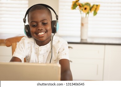 Front view of African American boy playing game on digital tablet at dining table in kitchen at home - Powered by Shutterstock