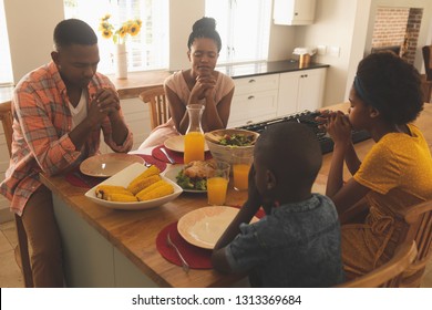 Front view of African American family praying together at dining table at comfortable home. Social distancing and self isolation in quarantine lockdown for Coronavirus Covid19 - Powered by Shutterstock