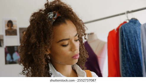 Front view of African American female fashion designer looking at cloth samples in workshop. She is examining clothe samples 4k - Powered by Shutterstock