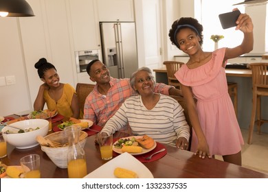 Front view of African American happy girl taking a selfie of her family at the dinning table with her mobile phone at home - Powered by Shutterstock