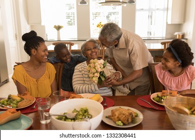 Front view of African American senior man giving a beautiful flower bouquet to his wife. Social distancing and self isolation in quarantine lockdown for Coronavirus Covid19
