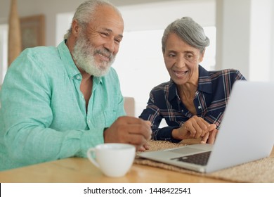 Front view of African-American couple using laptop on table inside a room indoor. Authentic Senior Retired Life Concept