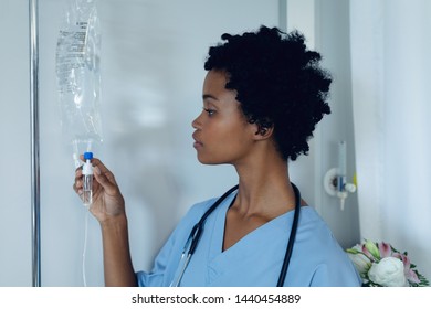 Front view of African-American female doctor adjusting iv drip in the ward at hospital - Powered by Shutterstock