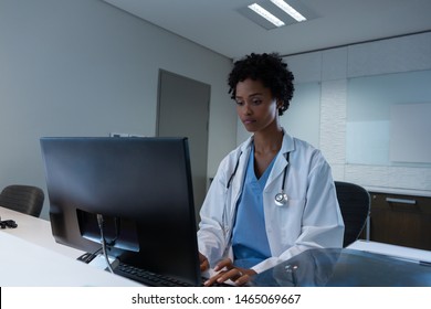 Front View Of African-american Female Doctor Working On Computer At Desk In Hospital. Healthcare Workers In The Coronavirus Covid19 Pandemic
