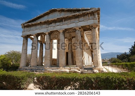 Front view of the ancient Doric Temple of Hephaestus above green hedges in Athens.