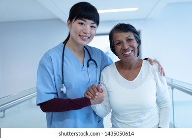 Front view of Asian female doctor standing with mixed-race female patient in the corridor at hospital