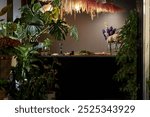 Front view background image of counter in elegant flower shop decorated with lush plants in low lighting, copy space