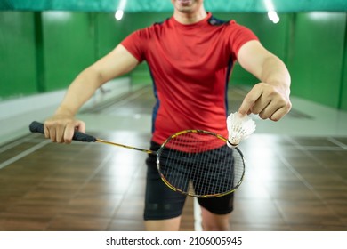 Front view of badminton player's hand holding shuttlecock and racket