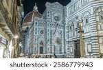 Front view of the Basilica di Santa Maria del Fiore night . Cathedral church (Duomo) of Florence in Italy. Evening illumination. Bell tower and dome. People sitting in the restaurant outside