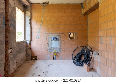 Front view of a bathroom under construction. There is a reel of black tube on the right. The old walls have been torn down, new walls still rough. Nobody inside - Powered by Shutterstock