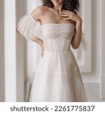 Front view of beautiful bride in the white wedding dress. Gorgeous wedding dress with stylish sleeves decorated with lace. Wedding lacy corset with cleavage