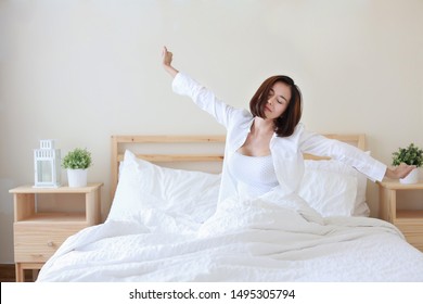 front view beautiful and healthy young asian woman wake up in the morning, she stretching after wake up in the morning on white bed in bedroom - Shutterstock ID 1495305794