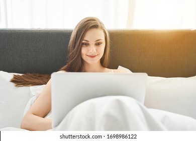 Front view of a beautiful young Caucasian lady with a pleased smile surfing the net - Shutterstock ID 1698986122