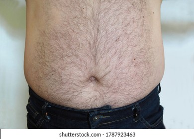 front view of the belly with the hair of a man in blue jeans. the problem of excess weight