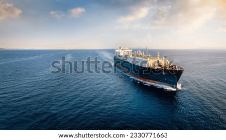 Front view of a big LNG tanker ship traveling with full speed over the ocean during sunset with copy space