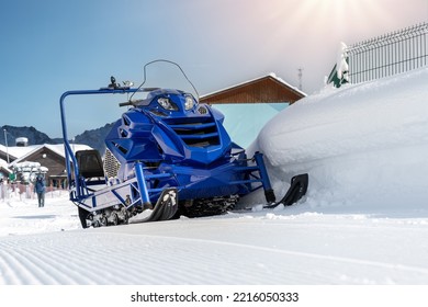 Front View Big Modern Snow Mobile Scooter Atv Alpine Mountain Reosrt Against Sunny Sky On Cold Snowy Winter Day. Snowmobile Rental Sport Adventure Trip Service. Arctic Nordic Snow Sledge Transport