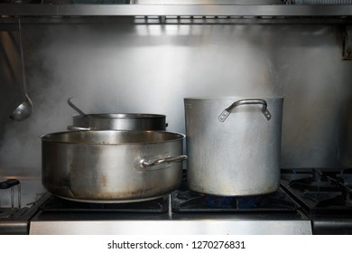 Front View Of Big Steel Pot And Saucepan On Burning Stove Top Smoking Boiling Water Full Length Front View