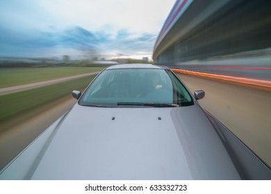 Front view of black car driving on high speed on a city at day time.
