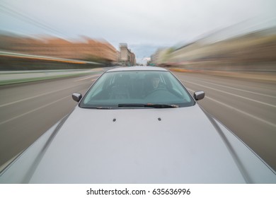 Front view of black car driving on high speed on a city at day time.