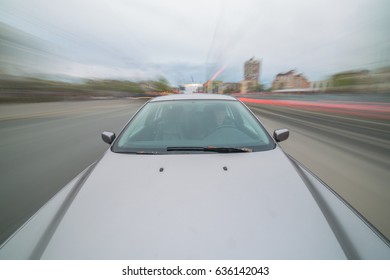 Front view of black car driving on high speed on a city at day time.