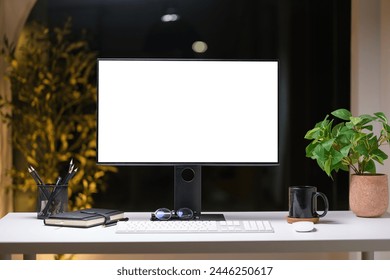 Front  view blank monitor, notebook and coffee cup on desk in dark room. 