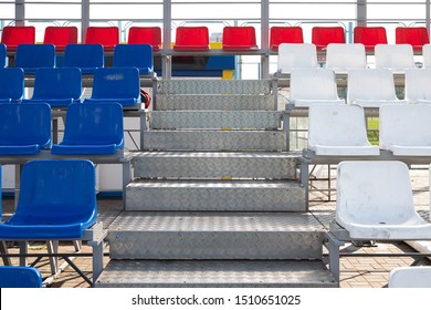 Front view of blue and red plactic seats on sport stadium's grandstand with metal steps