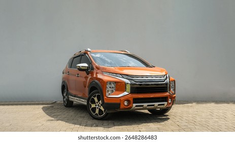 Front view of a bold orange SUV parked on pavement, featuring a futuristic design with black and chrome accents.