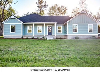 Front View Of A Brand New Construction House With Blue Vinyl Siding, A  Ranch Style Home With A Yard