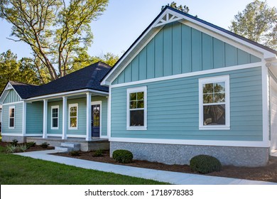 Front view of a brand new construction house with blue vinyl siding, a  ranch style home with a yard