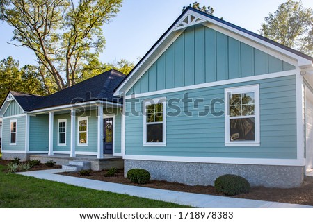 Front view of a brand new construction house with blue vinyl siding, a  ranch style home with a yard