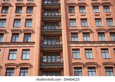 Front view of brick wall red contemporary apartment building with windows and balconies closeup