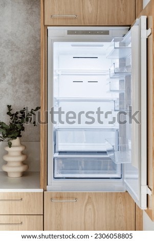 Front view of built in new fridge with open door, empty shelf and light inside. Modern kitchen with beige wooden cabinet furniture and stylish interior, household appliances Foto d'archivio © 