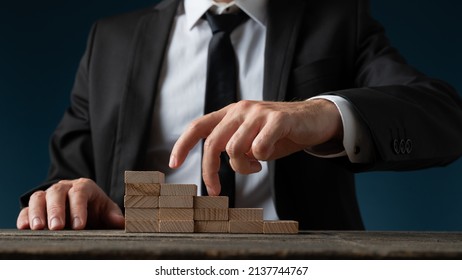 Front View Of A Businessman Walking His Fingers Up The Steps Made Of Wooden Pegs In A Conceptual Image Of Promotion And Success.