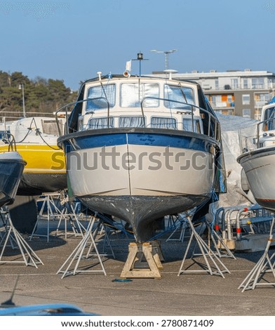 Front view of cabin boat elevated on stands in dry dock marina area